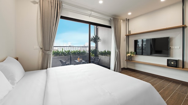 Une chambre d’hôtel moderne dotée d’un grand lit, d’un téléviseur fixé au mur et d’un balcon avec des meubles d’extérieur.