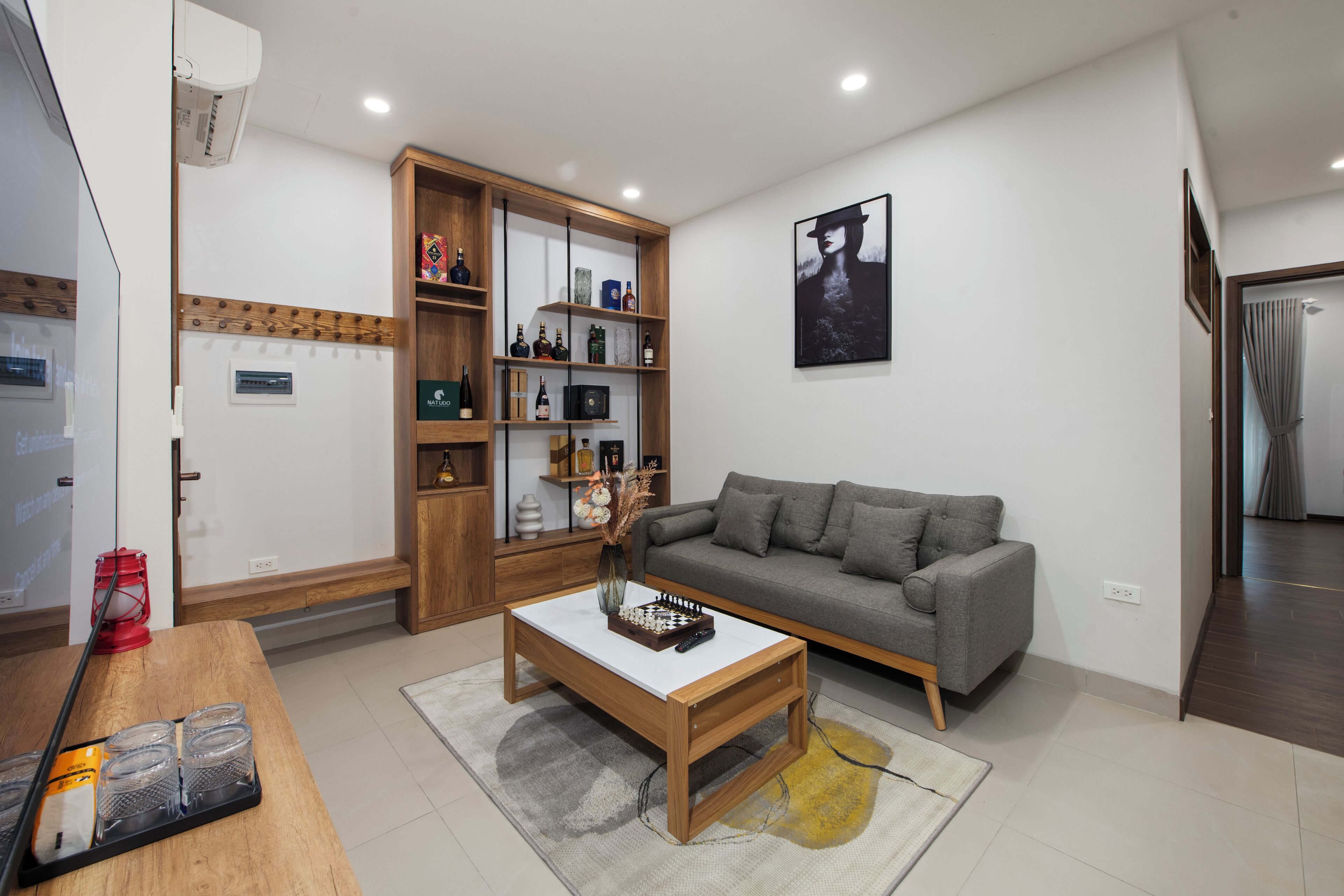 A modern living room with a grey sofa, wooden coffee table, and a bookshelf.