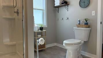 A bathroom with a shower, toilet, and shelves with towels.
