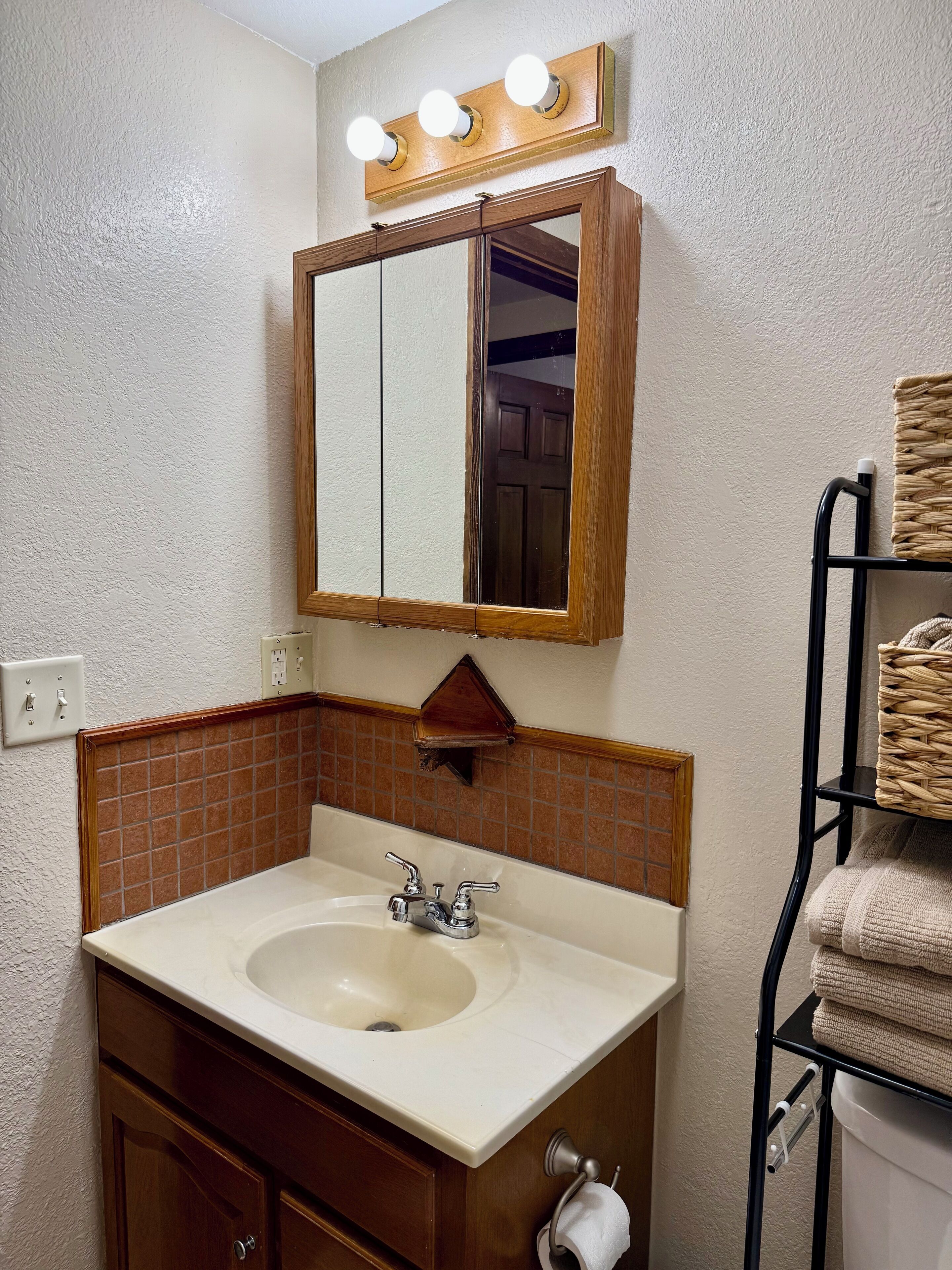 A bathroom with a sink, mirror, and towel rack.