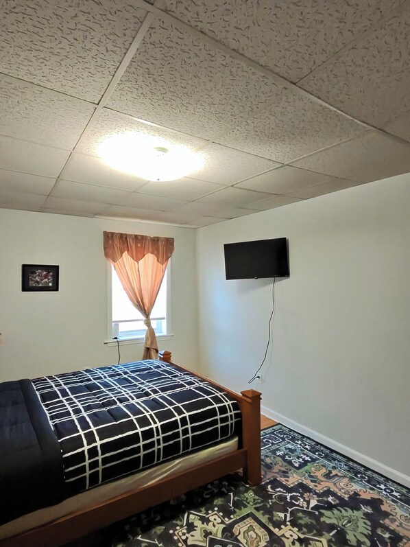 A bedroom with a bed, a television mounted on the wall, and a window with curtains. - Fall River Stay Cozy 4BR sleeps 8 + Free Parking + WiFi (Fall River)