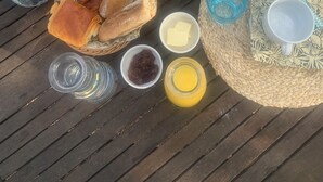 A table with various food items and utensils, including bread, butter, jam, and coffee, arranged on a woven mat. - Guest room 25m2 (Figari)