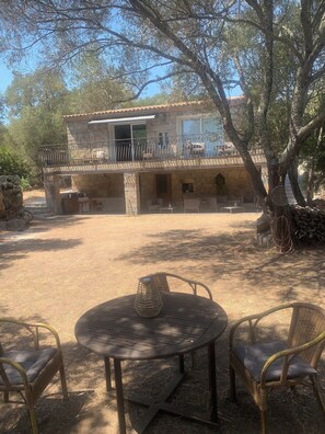 A stone building with a balcony, outdoor seating, and a tree in the foreground. - Guest room 25m2 (Figari)