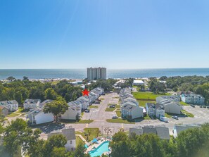 Un quartier résidentiel situé sur la côte, avec un grand immeuble en arrière-plan, une piscine et un parking.