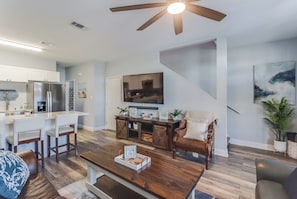 A modern kitchen with white cabinets, a stainless steel refrigerator, and a dining area with white chairs.