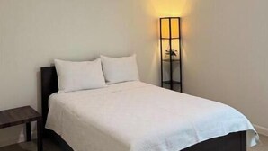 Una camera da letto con un letto, un comodino, una lampada da terra e una ventola a soffitto.