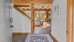 A modern interior with a wooden ceiling, a staircase, a kitchen area, and a fireplace.