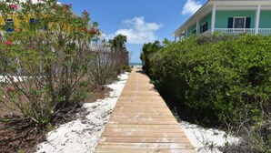 A wooden pathway leading to a beach with a clear sky.