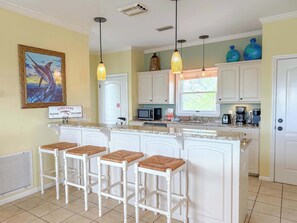 Cozinha com ilha central, armários brancos e um letreiro com a palavra 'lagostas'.