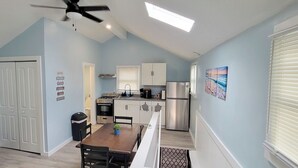 Una cocina compacta con electrodomésticos modernos, un comedor con mesa de madera y un ventilador de techo.