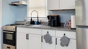 Una cocina moderna con armarios blancos, un refrigerador de acero inoxidable, horno empotrado y estufa a gas.