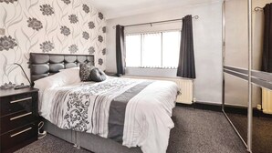 A bedroom with a bed, a dresser, a mirror, and a window with curtains. - Spacious 3 Bed 2 Baths Free WiFi Central Location (MIDDLESBROUGH)