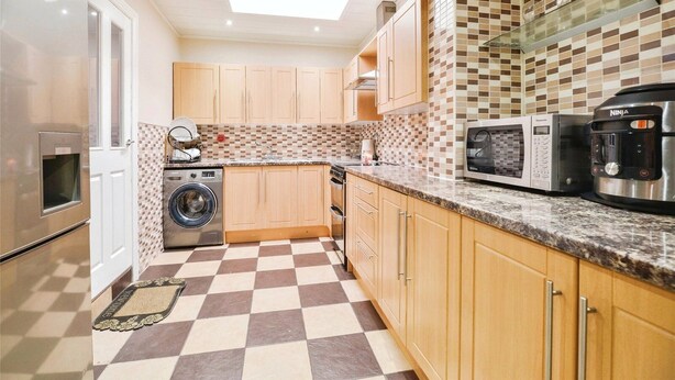 A compact kitchen with wooden cabinets, a washing machine, a microwave, and a coffee maker. - Spacious 3 Bed 2 Baths Free WiFi Central Location (MIDDLESBROUGH)