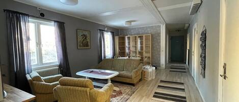 A living room with a sofa, armchairs, a coffee table, and a bookshelf.