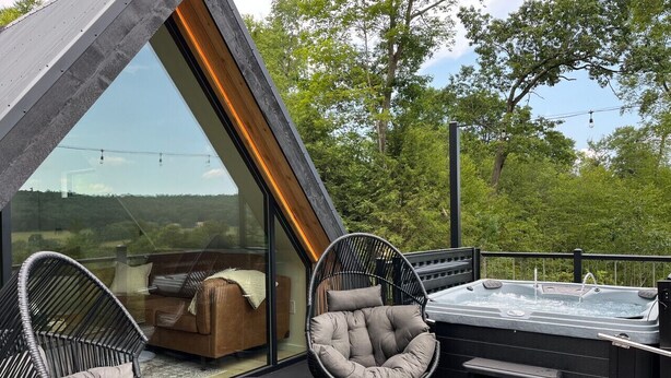 Een modern terras buiten met een hottub, twee comfortabele stoelen en een loungebank.