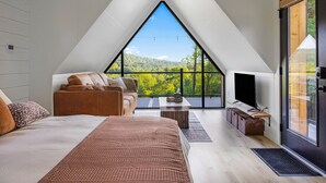 Een moderne loft slaapkamer met een groot dakvenster, een comfortabele bank, een flatscreen televisie en een houten salontafel.
