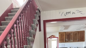 A staircase with red balusters leading to a dining area with wooden chairs and a table. - Charming 4-bedroom house with WiFi, AC in wonderful Sundance (Sundance)