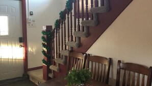 A staircase with wooden railings and garland decorations, leading to a dining area with a wooden table and chairs. - Charming 4-bedroom house with WiFi, AC in wonderful Sundance (Sundance)