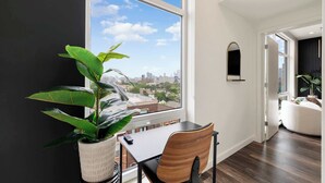 A modern room with a large window, a dining table, a chair, and a potted plant. - Downtown Chicago Retreat 2BD/2BA Views+Gym+Rooftop (Chicago)