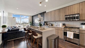 A modern kitchen with a central island, bar stools, a stove, and a microwave. - Downtown Chicago Retreat 2BD/2BA Views+Gym+Rooftop (Chicago)