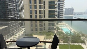 Un balcon avec une table et des chaises donnant sur une marina et des immeubles de grande hauteur.