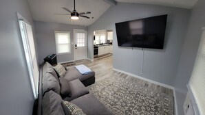 A living room with a sofa, a flat-screen TV mounted on the wall, and a ceiling fan. - GOTL Lovers Chateau Cottage U7 (Geneva)