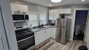 A modern kitchen with stainless steel appliances, white cabinets, and a wooden floor. - GOTL Lovers Chateau Cottage U7 (Geneva)