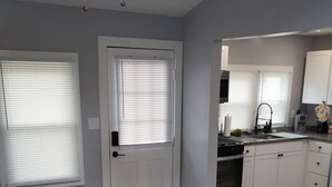 A modern living room with a gray sofa, a patterned rug, and a door leading to a kitchen area. - GOTL Lovers Chateau Cottage U7 (Geneva)