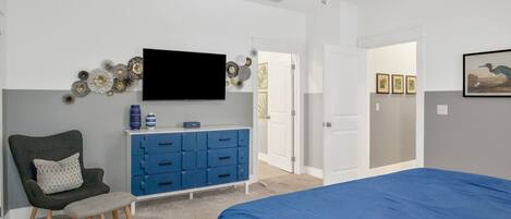 A bedroom with a bed, a TV, a dresser, and a chair.