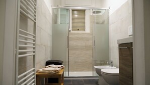 A modern bathroom with a glass shower enclosure, a wooden bench, a toilet, and a sink.