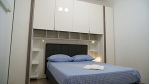 A bedroom with a bed, a wardrobe, and a nightstand.