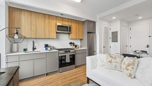 A modern kitchen with built-in appliances, a white sofa, and a glass coffee table. - Chic studio with fitness room, WiFi in delightful Brooklyn (Brooklyn)