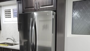 A stainless steel refrigerator in a kitchen with dark wooden cabinets and a white countertop. - Cozy Private Oasis Peaceful Stay (Milton)