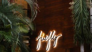 A neon sign with the word 'flying' on a wooden wall surrounded by tropical plants. - Aura Luna Tropical Rooftop Beach Club Access (Tulum)