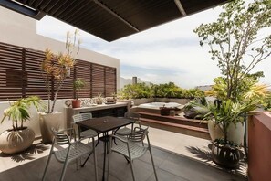 Eine Terrasse im Freien mit Tisch und Stühlen, Blumentöpfen und einer Sitzecke.