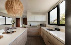 A modern kitchen with a central island, white cabinets, and a large window.