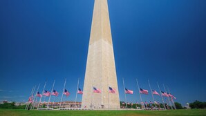 A tall obelisk with American flags in front.