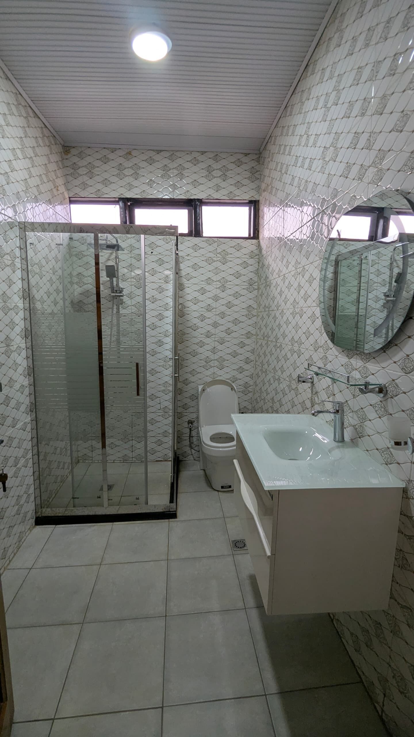 Une salle de bain avec une douche à parois de verre, des toilettes et un lavabo avec un miroir.