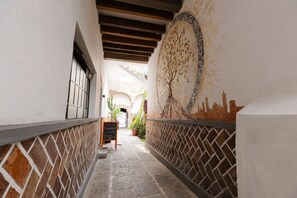 A corridor with a tiled floor, a mural on the wall, and a signboard.