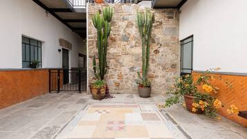 A courtyard with a stone wall, potted cacti, and a tiled floor.