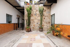 A courtyard with a stone wall, potted cacti, and a tiled floor. - Casona 212 | Design & Connectivity Near Downtown (Heroica Puebla de Zaragoza)