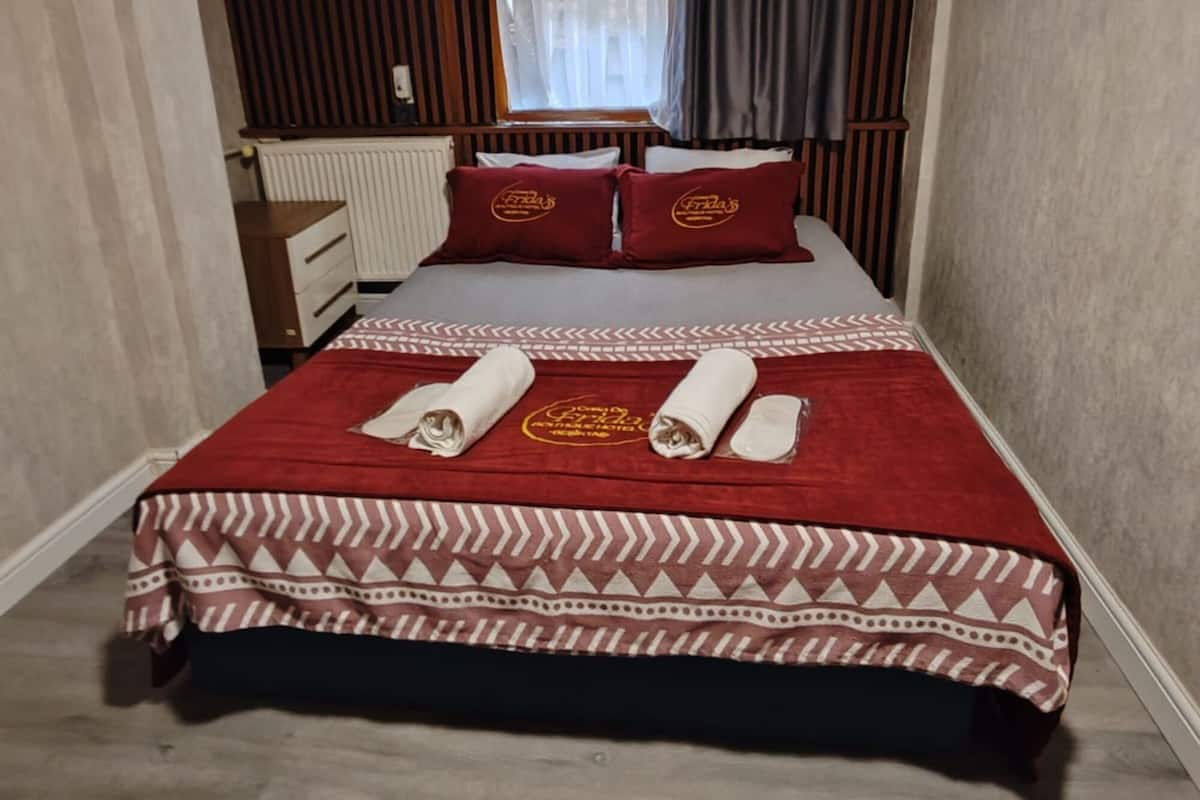 A hotel room with a bed, a desk, and a window with curtains.