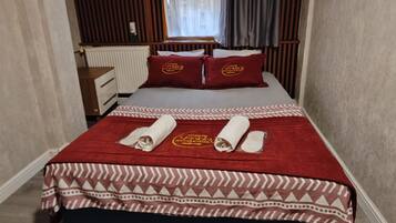 Habitación de hotel con cama, escritorio y ventana con cortinas.