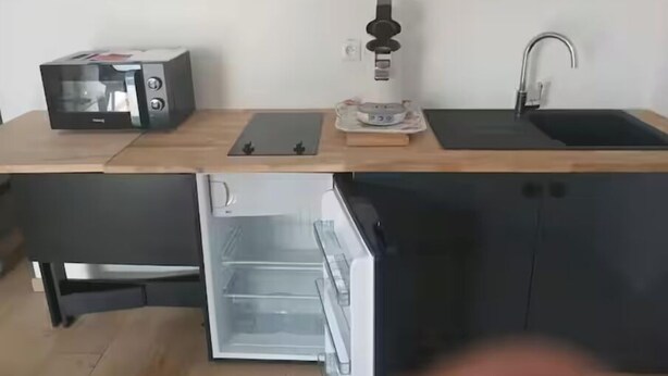 Cocina compacta con microondas, cafetera y un mini refrigerador integrado.