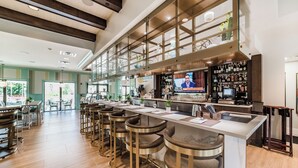 Un moderno bar con una barra larga, varios taburetes y una pantalla de televisión.