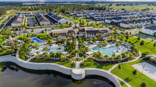 Vista aérea de una zona residencial con piscina central, rodeada de casas y un parque con áreas de juego.