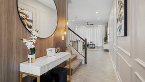 Un pasillo moderno con un aparador blanco, un espejo grande y una escalera que lleva a una habitación.