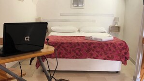 Ein Schlafzimmer mit einem Bett, einem Laptop auf einem Schreibtisch und einem Rasenmäher im Vordergrund.