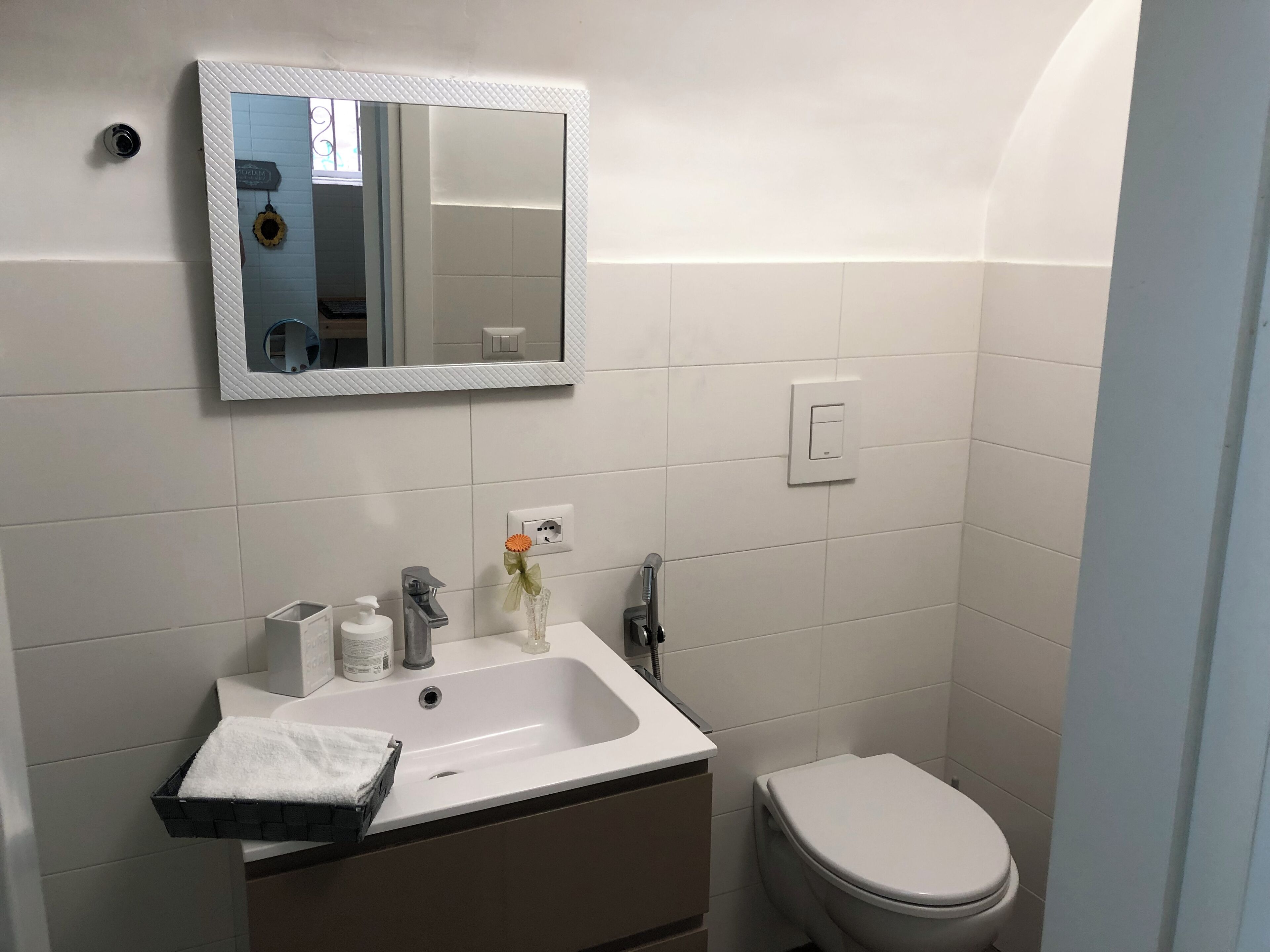 A bathroom with a white sink, mirror, and toilet.