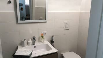 A bathroom with a white sink, mirror, and toilet.